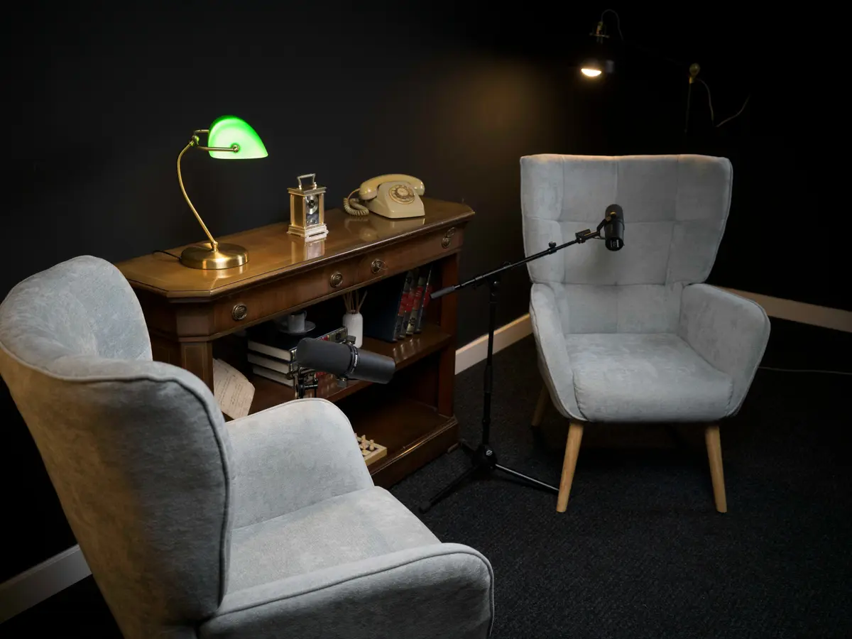 Sala negra con sillones, lámpara de banquero y teléfono antiguo